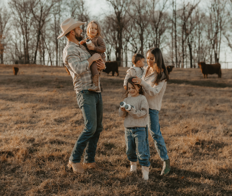 Family standing on a grass fed cattle farm